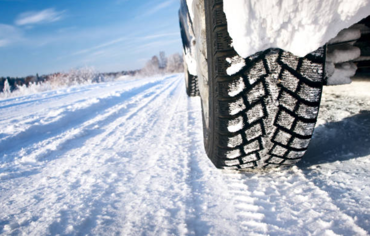 A close-up view of a truck tire driving through the snow.